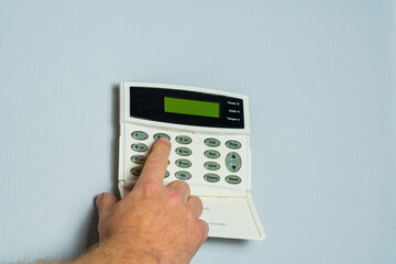 Hand keying in the security code on a residential property alarm panel, Home burglary or crime...