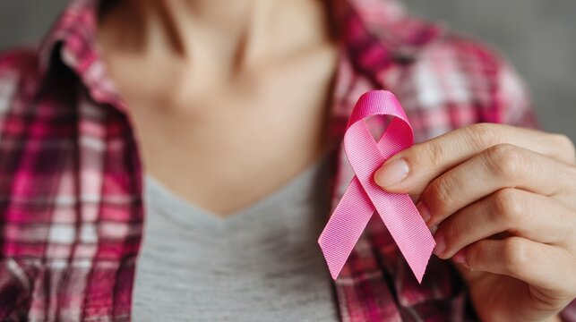 October is Breast Cancer Awareness Month a woman holds a pink ribbon and wears a supportive shirt It also coincides with National Cancer Survivors Month and World Cancer Day