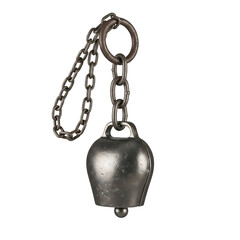 A vintage metal cowbell with a rustic chain hanging from a ring isolated on a stark black background evoking a sense of tradition and rural life