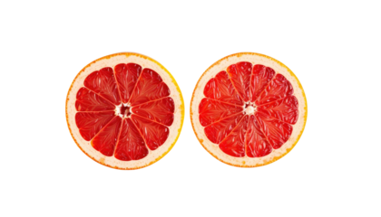 Two halved grapefruit slices facing upward with red flesh against a contrasting black background