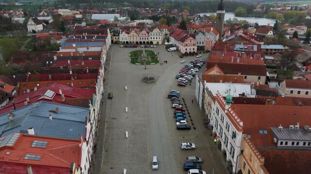 Drone perspective flying high over the historic UNESCO World Heritage Site of Telč, highlighting the colorful gabled houses and arcades lining Zacharias of Hradec Square.