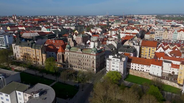 Aerial View Moving Down Towards Safarikovy Sady Park and Gardens in Pilsen, Bohemia, Czech Republic, Highlighting Lush Green Trees and People Enjoying the Sunny City Center.