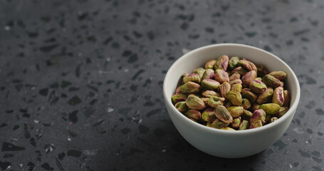 peeled pistachios in white bowl on terrazzo surface