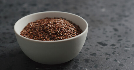 flaxseed in white bowl on terrazzo countertop with copy space