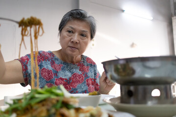 An Elderly Woman Happily Enjoying A Bowl of Noodles in a Cozy Restaurant Setting