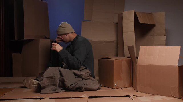 Homeless man experiencing despair and poverty holding bottle of alcohol