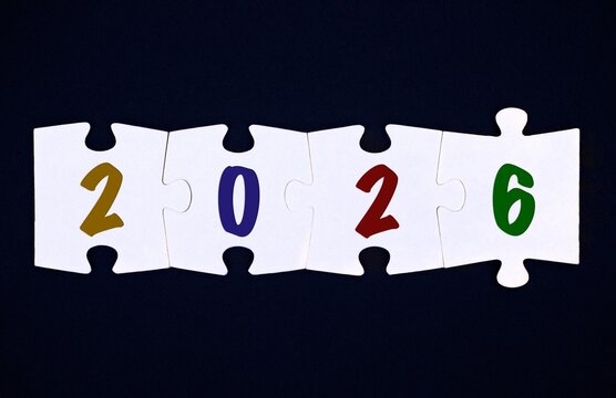 Four pieces of puzzle with numbers 2026 on black background - Powered by Adobe