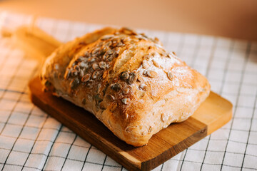 Freshly baked bread with watermelon seeds on a wooden cutting board in a cozy kitchen setting