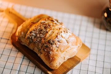 Fresh bread baked with watermelon seeds on a wooden cutting board and soft lighting