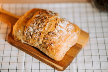 Fresh bread topped with watermelon seeds on a wooden board in a cozy kitchen setting