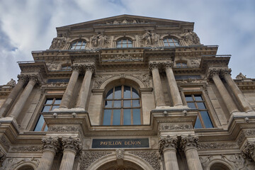 Classical facade of the Louvre Museum in Paris with cloudy skies and symmetrical architecture in a heritage and cultural setting