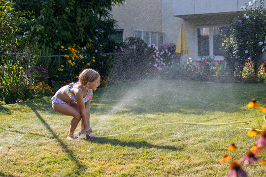 girl hoses herself down in the backyard.