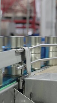 Tomato sauce cans on a conveyor belt in a canned food production facility