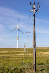 Power lines line up with a wind turbine in the steppe of Kazakhstan
