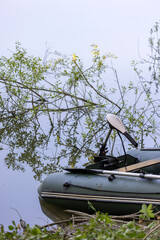 a green rubber boat with an electric motor on the river bank
