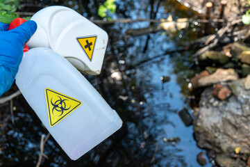 Collection of radioactive waste on the coast.Work as a volunteer.A hand in a blue glove with trash.A biohazard sign on the bottle.