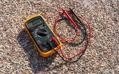 The digital multimeter is lying on the rocks, top view.A device for measuring voltage power.