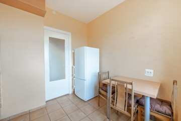 Cozy Wooden Kitchen Home Interior. Fridge and Dining Table in Background. Tile Floor