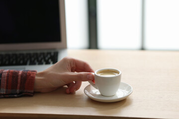 Woman having coffee break at wooden desk indoors, closeup. Space for text