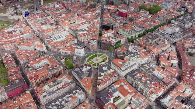 High angle tripod view of Plaza Moyua, roundabout in the center of Bilbao, Basque Country, surrounded by historical buildings with red tile roofs