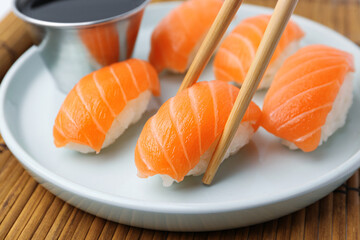 Taking delicious nigiri sushi with chopsticks from plate, closeup