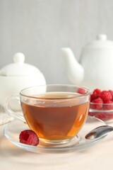 Delicious tea and raspberries on white table, closeup