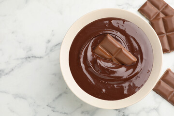 Melted chocolate and pieces on white marble table, flat lay. Space for text