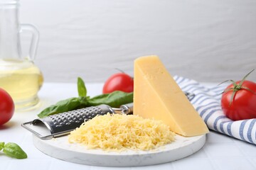 Grated cheese, grater and products on white table, closeup