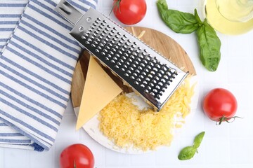 Grated cheese, grater and products on white tiled table, flat lay