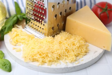 Grated cheese, grater and products on white table, closeup