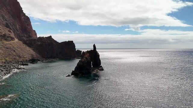 Orbiting aerial drone view circling the iconic Roque de La Bonanza sea stack off the volcanic coast of El Hierro, Canary Islands.