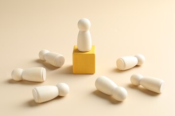 Winner. Human figures, wooden one on top of yellow cube against beige background, closeup