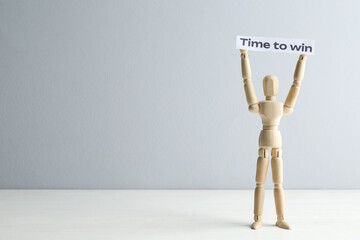 Human figure holding paper note with phrase Time To Win on white wooden table against light grey background, space for text