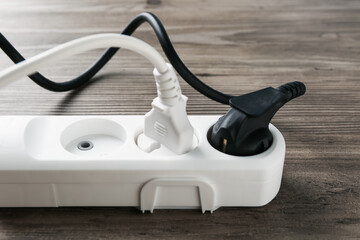 Power strip with electrical plugs on wooden table, closeup