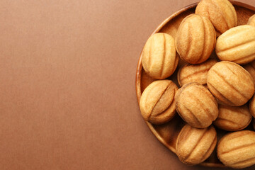 Delicious nut shaped cookies with boiled condensed milk on brown background, top view. Space for text