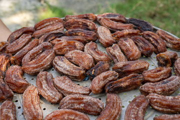 Close up of traditional Indonesian sun-dried bananas (Sale Pisang) on a metal tray. Homemade sweet snack being dried outdoors in the sun.
