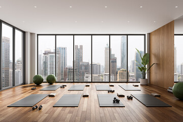 Modern yoga studio interior with exercise mats and equipment overlooking urban skyline through large windows, featuring wooden flooring and minimalist decor. 3D Rendering