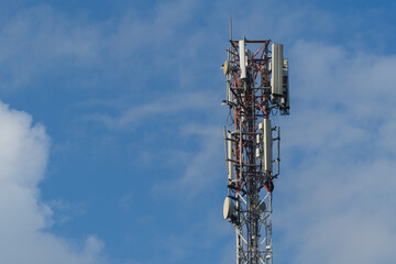 Telecommunication tower (BTS) with 4G/5G antennas for mobile internet and signal. Blue sky with clouds background.