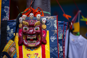 Handmade colorful tribal look face mask souvenir hanging on plain background. Selective focus on object.