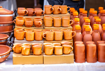 Colorful coffee or tea cups on shelf against ceramic items blur background.