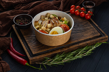 Caesar salad with chicken in disposable bowl