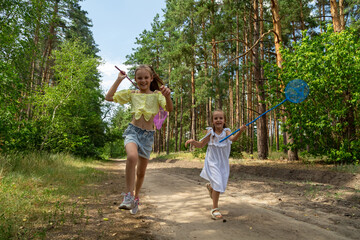 Fototapeta premium Two little girls catching insects with nets in forest