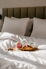 Enjoying a cozy breakfast in bed with pastries and coffee on a relaxing morning
