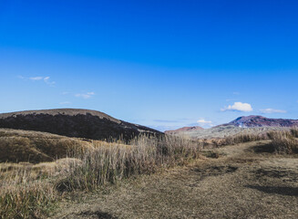 Vast Barren Plateau with Volcanic Slopes and Dry Grass under a Bright Blue Sky