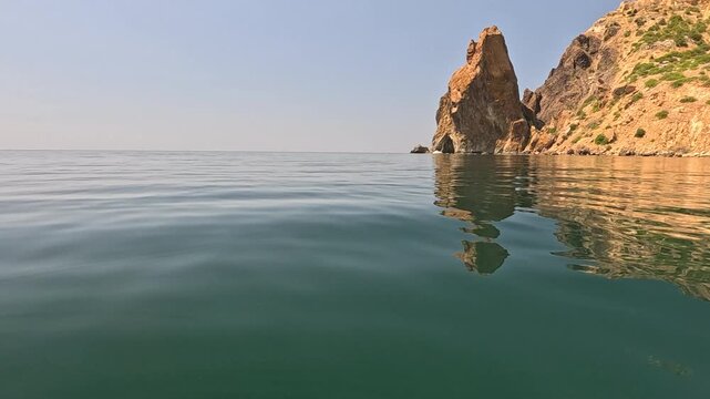 Sea Cliff Water, calm ocean waves reflecting rugged mountain in serene natural landscape on a sunny day