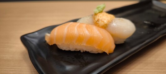 Sushi on a black plate on a wooden table