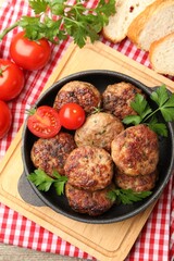 Delicious patties with parsley, tomatoes and bread on wooden table, top view