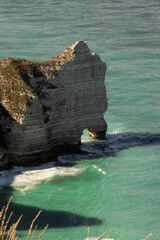 Steep white cliffs overlooking the calm sea at Étretat, Normandy. Majestic coastal landscape under a soft cloudy sky, symbolizing natural beauty and serenity.
