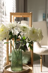 Beautiful white chrysanthemum flowers in vase on wooden shelf indoors
