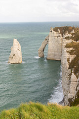 Famous white cliffs of Étretat, Normandy, France, rising above turquoise sea waters. Iconic coastal landscape known for its natural beauty and dramatic rock formations.